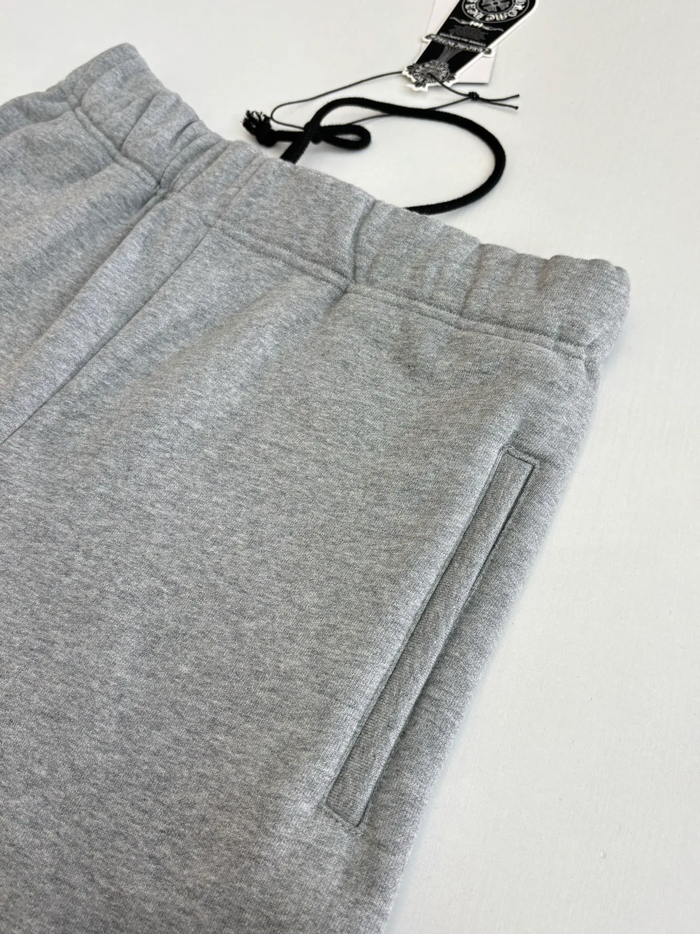 P346 Chrome Hearts*/Chrome Hearts 26SS early spring new patch embroidered shorts The fabric is made of a blended ratio of 80% cotton and 20% polyester. It is woven with a siro spinning process of 32-count base yarn and 10-count veil to form a high-weight terry cloth base of 380g/㎡. The cotton-polyester blended material combines the skin-friendly breathability of cotton and the anti-wrinkle shape retention of polyester. The high-weight fabric gives the trousers excellent stiffness and drape. The core technology is patch embroidery, which is completed with the help of TAJIMA computer embroidery machine. The black special-shaped patch is precisely sewn to the trouser fabric through lock stitches. The embroidery stitch density is even and the edges are neatly hemmed, forming a three-dimensional relief-like visual effect. Size: S/M/L/XL